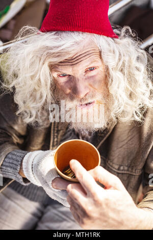 Pauvres malheureux homme tenant une tasse avec des pièces Banque D'Images