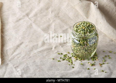 Petits pois crus dans un bocal en verre sur la nappe de fabrication locale, close-up, selective focus. Certains copie espace pour votre inscription. Protéines organiques. Perfect ingredie Banque D'Images