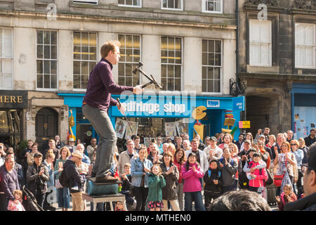 Artiste de la rue de sexe masculin jonglant avec un couteau et des haches tout en équilibrant en face de grande foule sur le Royal Mile d'Édimbourg, Écosse, Royaume-Uni Banque D'Images