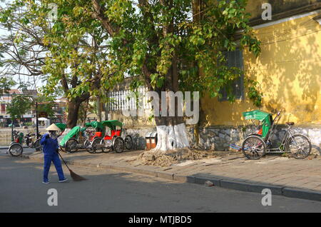 HOI AN, VIETNAM - 20ème Mars 2018 : balayeuse travailleur avec un balai nettoyage de la rue au centre de la ville du patrimoine mondial de l'Hoi An Banque D'Images