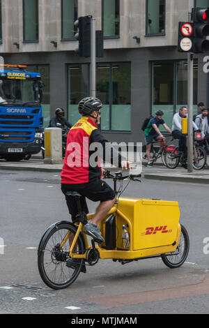 Un cavalier livraison DHL dans le centre de Londres pour faire du vélo ou du vélo dans la ville de distribuer les lettres et paquets. Ville de Londres services de courrier DHL. Banque D'Images