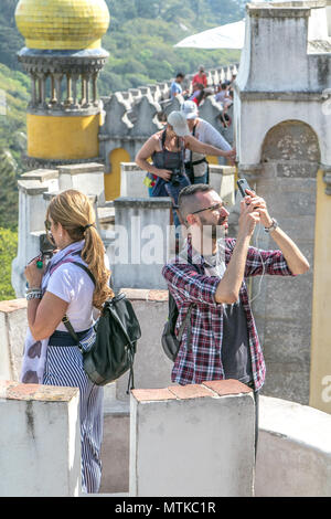 L'homme et la femme sont à prendre des photos des palais de Pena à l'aide de leurs smartphones. Sintra, Portugal. Banque D'Images