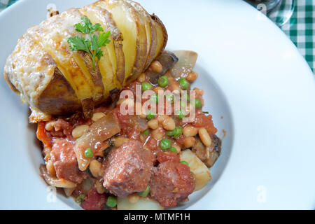 Une partie de Corned Beef hash servi avec un fromage surmontée de pommes de terre Hasselback Banque D'Images