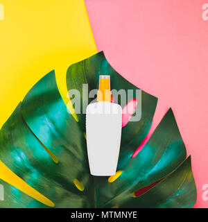 Jungle tropicale Feuilles monstera palmier bouteille vide de l'écran solaire et immersive sur carré lumineux jaune et rose papier duotone arrière-plan. Vacances d'été cre Banque D'Images