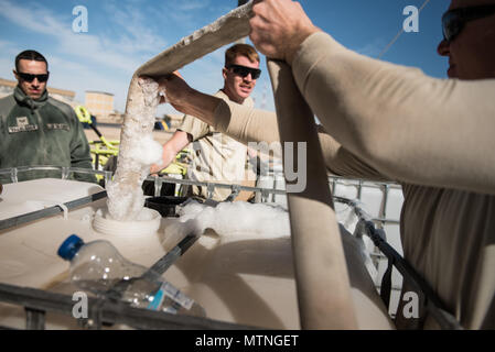 Tech. Le Sgt. Jason Demoss, 407e Escadron de génie civil de la Force expéditionnaire du chef adjoint de l'incendie, des racloirs de mousse agité un tuyau d'incendie lors du transfert d'un produit ignifuge avec remorque mousse aviateur Senior Francisco Villalobos (à gauche) et le sergent. Clinton Manus, les deux éducatrices 407e les pompiers, au 407e groupe expéditionnaire aérienne, le 6 janvier 2016. Le concentré de mousse est mélangé avec de l'eau et l'air en cas d'incendie et d'aéronefs utilisés pour étouffer les flammes. (U.S. Air Force photo/Master Sgt. Benjamin Wilson)(1992) Banque D'Images