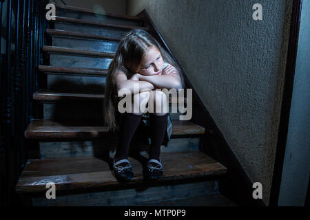 Triste, déprimé, malheureux lycéenne souffrant de l'intimidation et l'abus le sentiment de solitude et de désespoir assis sur les escaliers de lumière sombre. L'isolement de l'école, Banque D'Images