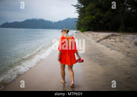 Une femme blonde déambule le long de la plage au Damai Laut en Malaisie. Banque D'Images