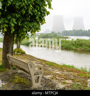 Centrale nucléaire de Belleville sur les bords de la Loire par temps brumeux avec un banc en béton sur le quai dans l'avant-plan. Banque D'Images