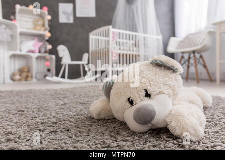 Vue d'un ours en peluche portant sur un tapis dans une chambre bébé fille Banque D'Images