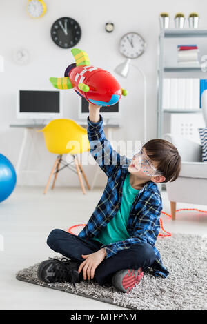 Prise d'un petit garçon assis sur un étage et jouer avec un jouet rocket Banque D'Images