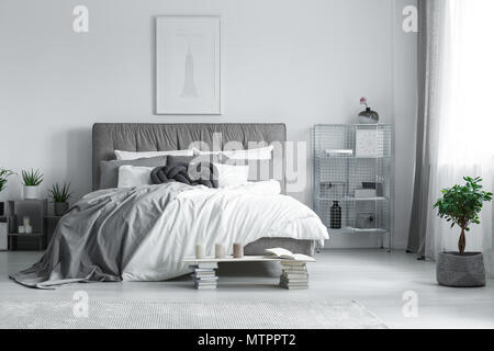 Gris et Blanc, cette chambre élégante avec la peinture accrochée au-dessus du lit king-size Banque D'Images