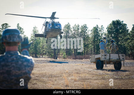 Un soldat de l'École d'assaut aérien DeGlopper, XVIII Airborne Corps guides dans un UH-60 Black Hawk affecté à la 2ème bataillon d'hélicoptères d'assaut, 82e Brigade d'aviation de combat qu'elle prépare pour connecter un remorque cargo charge sous élingue sur Fort Bragg, N.C., Jan 19. (U.S. Photo de l'armée par le Sgt. Steven Galimore) Banque D'Images