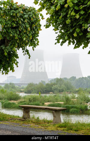 Centrale nucléaire de Belleville sur les bords de la Loire par temps brumeux avec un banc en béton sur le quai dans l'avant-plan. Banque D'Images