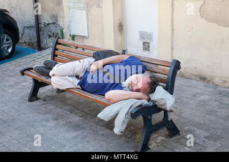 Homme avec barbe blanche endormie sur un banc en bois en Provence, France Banque D'Images