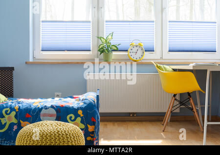Fragment d'un enfant avec grande fenêtre aveugle, sous couvert du radiateur, lit et bureau avec chaise à côté Banque D'Images
