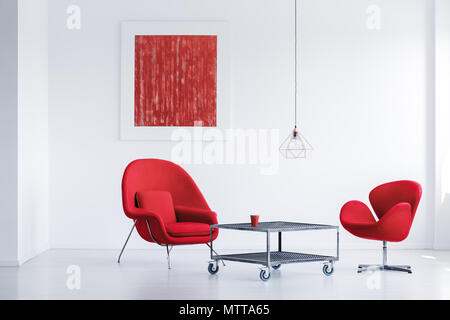 Simple blanc salle d'attente avec deux chaises rouges par la table industrielle Banque D'Images