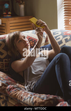 Belle femme en tenant sur selfies sofa in living room Banque D'Images