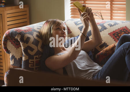 Belle femme en tenant sur selfies sofa in living room Banque D'Images