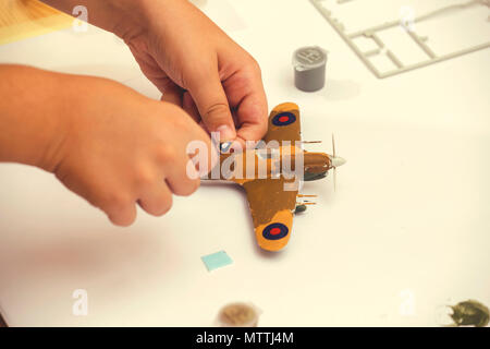 Garçon part l'application de l'autocollant toboggan plastic model de ww2 plan d'avions à la maison. Passe-temps et loisirs. Vintage style. Banque D'Images