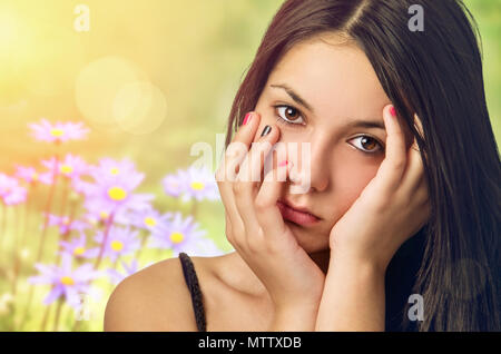 Belle adolescente sereine avec les mains de face, au printemps contexte flowery Banque D'Images