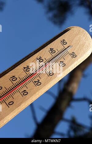 Haute température thermomètre montrant sur une chaude journée ensoleillée, avec un arbre et fond de ciel bleu clair Banque D'Images