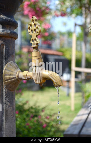 L'eau qui coule du robinet en bronze sur une chaude journée d'été. Vintage robinet. Banque D'Images