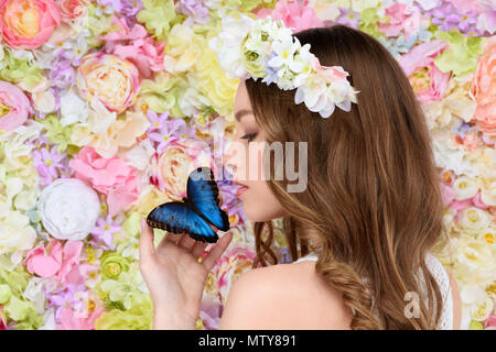 Jeune femme en couronne de fleurs avec papillons en main Banque D'Images
