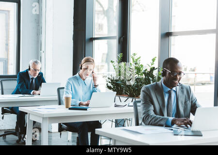 Les gens d'affaires professionnels multiethniques en utilisant les casques portables in modern office Banque D'Images