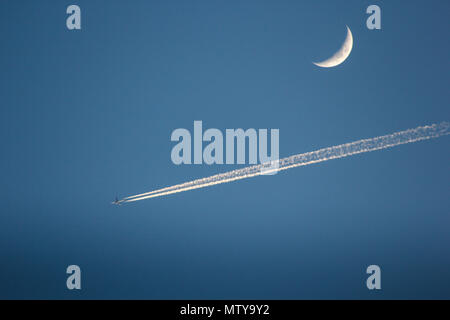 Jet Plane flying passé demi lune on blue sky Banque D'Images