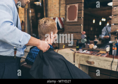 Coiffure debout avec client qu'assis en face du miroir en barber shop Banque D'Images