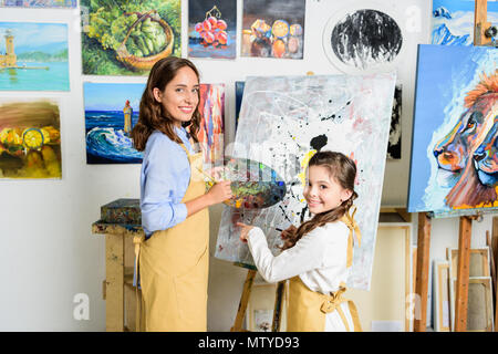 Professeur et élève debout près de toile dans l'atelier d'art school et looking at camera Banque D'Images