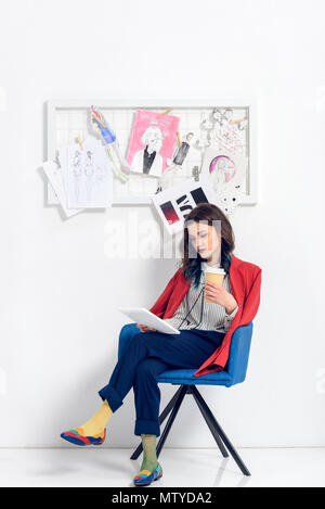 Jolie dame travaillant sur tablet et holding Coffee cup dans le Light Studio Banque D'Images