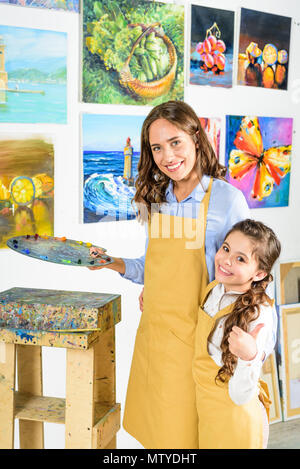 Étreindre l'enseignant élève et elle showing thumb up dans l'atelier de l'école d'art Banque D'Images