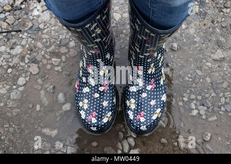 Femme portant des bottes wellington debout dans une flaque d'eau Banque D'Images