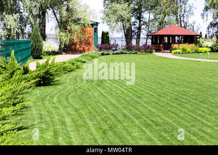 Rangées de tondre des pelouses vertes à résidence de campagne, avec un pavillon d'été. Frais de couverture des cèdres. La conception de paysage et concept de jardinage Banque D'Images