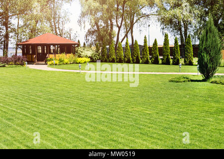 Rangées de tondre des pelouses vertes à résidence de campagne, avec un pavillon d'été. Frais de couverture des cèdres. La conception de paysage et concept de jardinage Banque D'Images