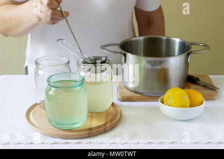 Des fleurs, de l'eau, de citron et de sucre, les ingrédients et une femme en train de préparer un sirop de sureau. De style rustique, selective focus. Banque D'Images