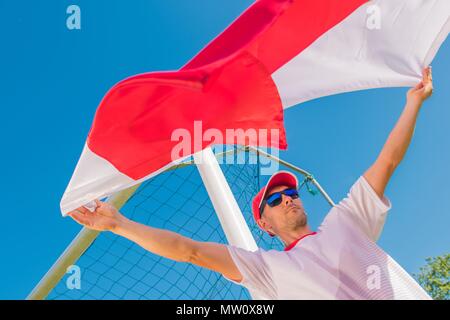 Caucasian Fan de foot avec le Polish drapeau rouge et blanc dans l'air. Banque D'Images