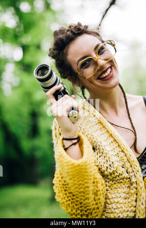 Portrait de jeune femme à l'aide d'une caméra de cinéma vintage dans un parc Banque D'Images