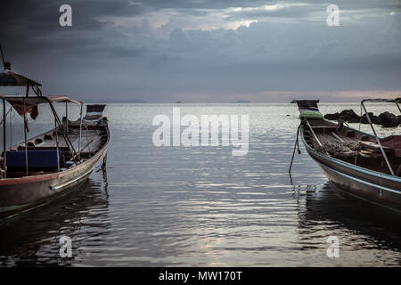 Style asiatique asiatiques traditionnels bateaux paysage dirigé vers l'horizon en mer calme pendant le coucher du soleil moody sombre Banque D'Images