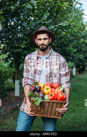 Barbu beau farmer holding panier avec des légumes biologiques frais Banque D'Images