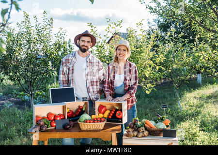 Deux smiling les agriculteurs qui vendent des légumes cultivés au cours du marché Banque D'Images