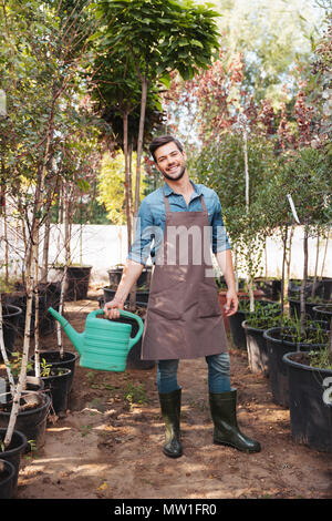 Jardinier smiling at camera while holding à bidon à la main dans le jardin Banque D'Images