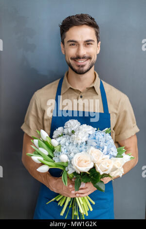 Beau male florist barbu dans apron holding beau bouquet de fleurs et smiling at camera Banque D'Images