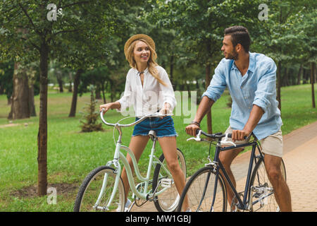 Happy young couple riding bicycles together in park Banque D'Images