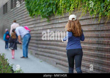 Young woman jogging le long de la rue en ville européen, dans la matinée. L'exécution de fitness petite fille contre un mur de briques Banque D'Images