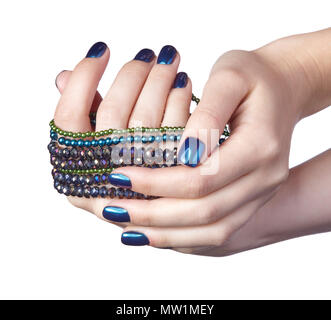 Femme avec perles Bijoux de costume. Les doigts avec un bleu brillant ongles manucure. Girl's hands avec bijouterie isolé sur fond blanc Banque D'Images