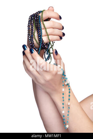 Femme avec perles Bijoux de costume. Les doigts avec un bleu brillant ongles manucure. Girl's hands avec bijouterie isolé sur fond blanc Banque D'Images