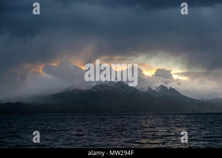 Grâce à une ouverture dans les nuages, le soleil montre son dernier feu de la journée derrière les montagnes du canal de Beagle, la partie chilienne. Banque D'Images