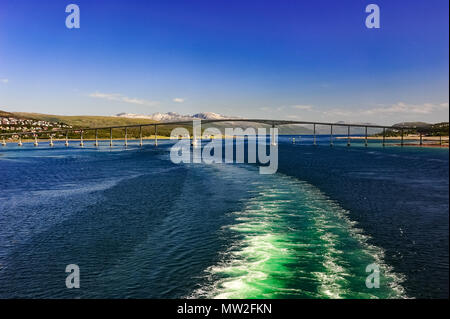 Service du navire sur Tromso Son avec vue de Tromso road bridge. La ville est dans la distance avec des montagnes enneigées et un ciel bleu clair Banque D'Images